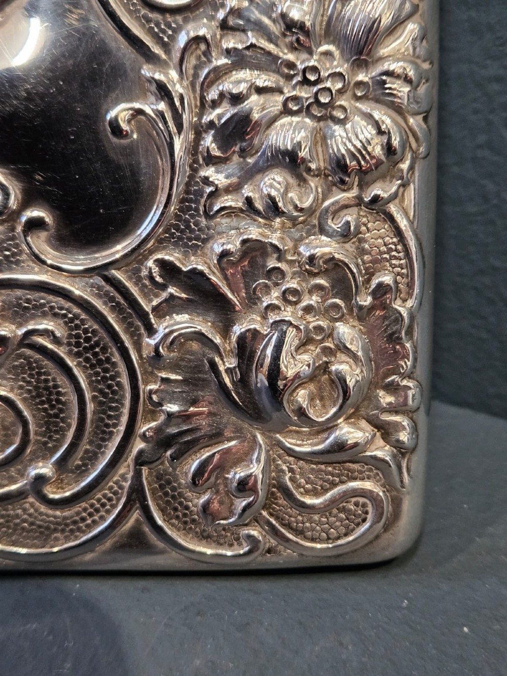 An Edwardian sterling silver hinged card case featuring intricate Art Nouveau repousse scrollwork and floral relief design. View II