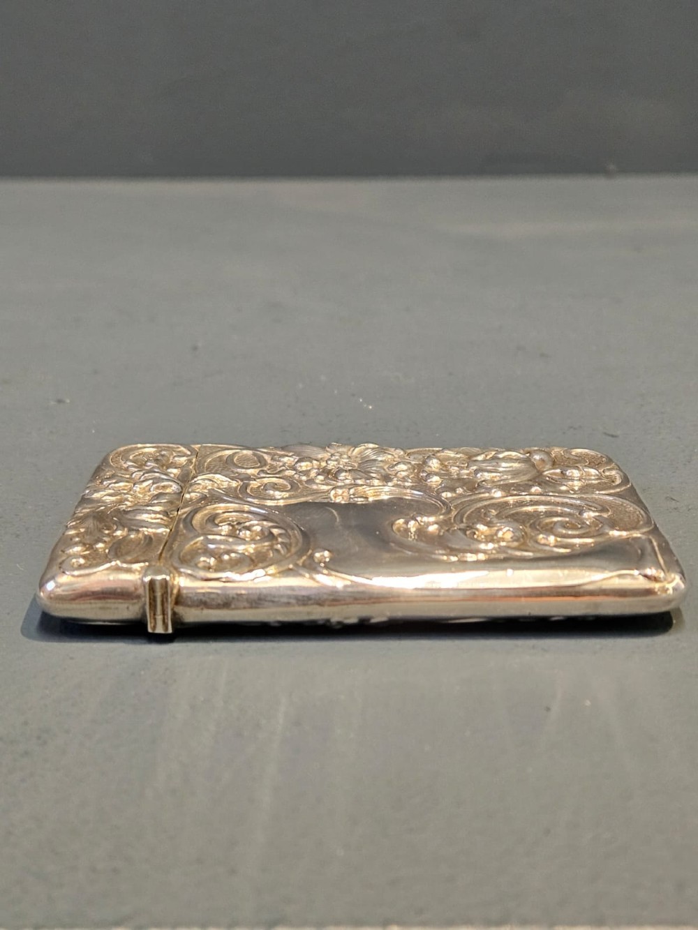 An Edwardian sterling silver hinged card case featuring intricate Art Nouveau repousse scrollwork and floral relief design. View VI