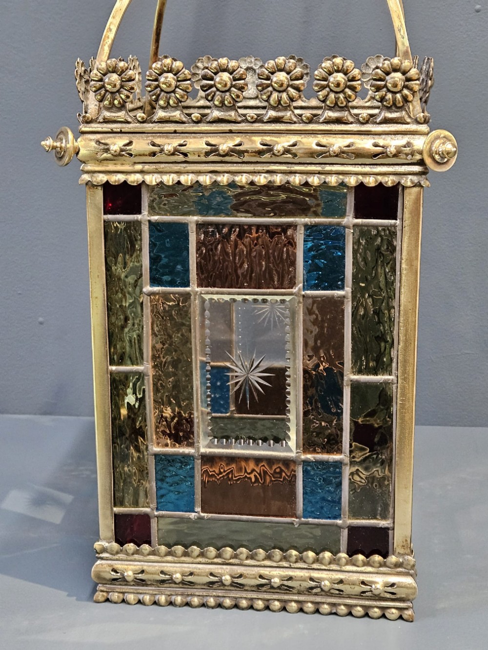 A Victorian brass hanging lantern featuring leaded stained-glass panels with starburst detailing and an ornate floral rim. View V
