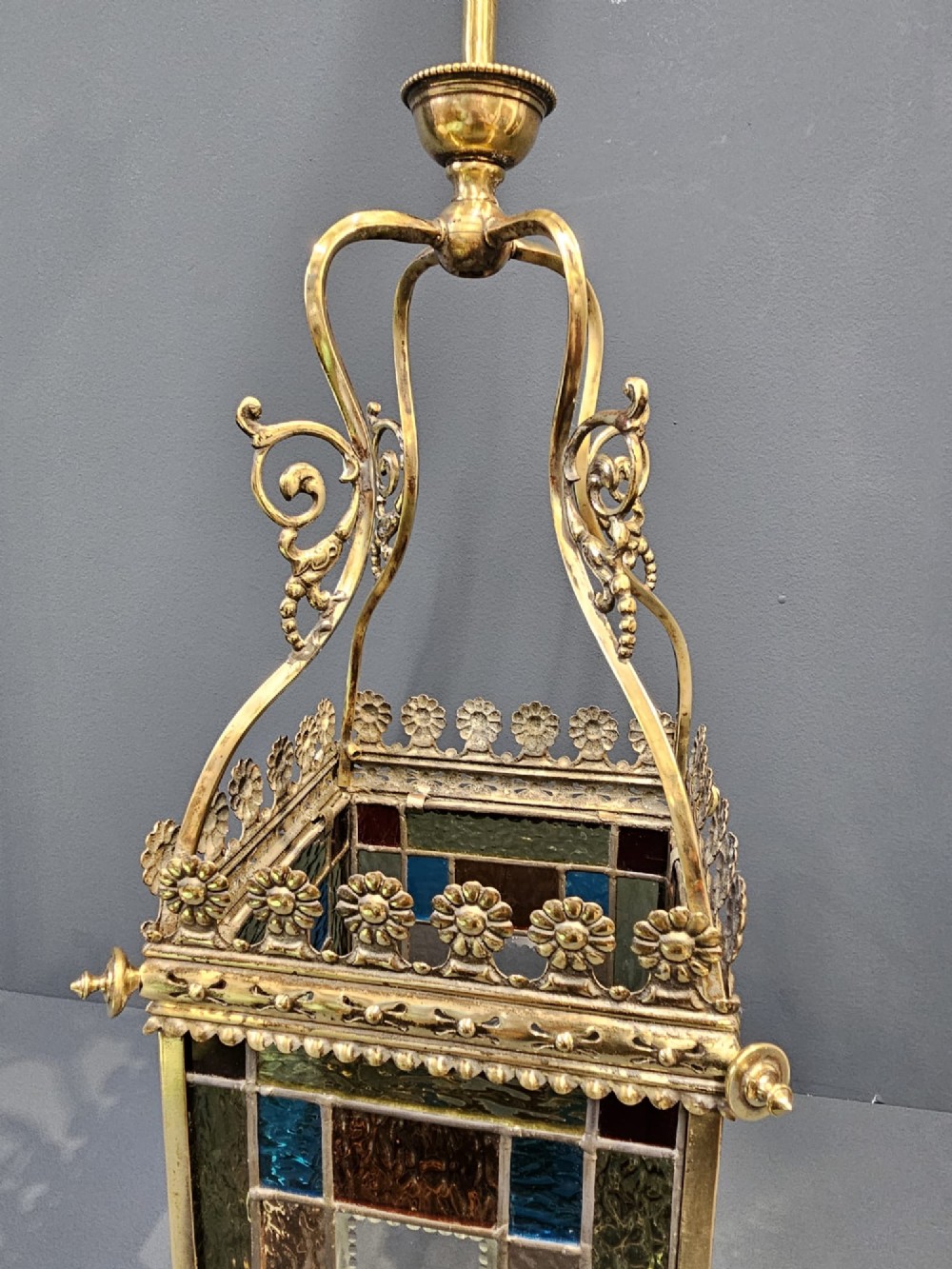 A Victorian brass hanging lantern featuring leaded stained-glass panels with starburst detailing and an ornate floral rim. View VI