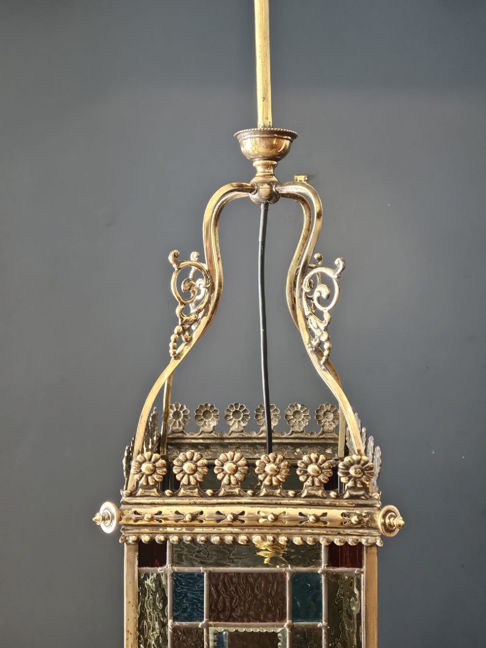 A Victorian brass hanging lantern featuring leaded stained-glass panels with starburst detailing and an ornate floral rim. View IX