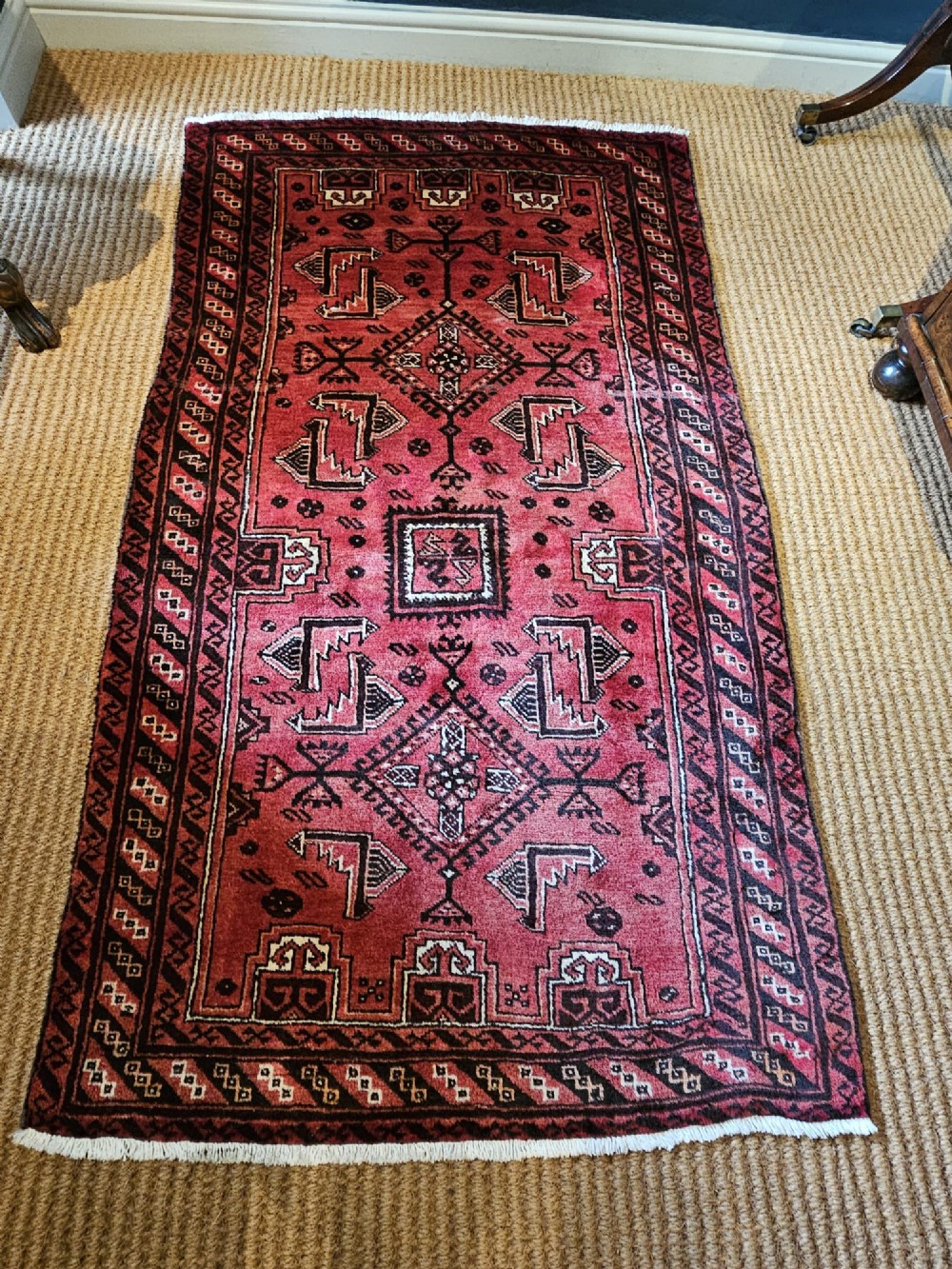 A hand-knotted deep red and dark brown Baluch tribal wool rug featuring geometric diamond medallions and short white fringe edges. View II