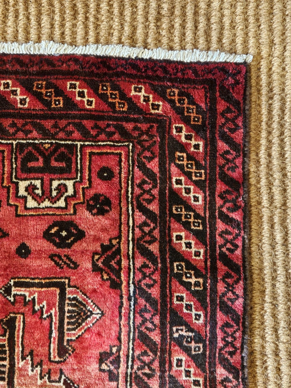 A hand-knotted deep red and dark brown Baluch tribal wool rug featuring geometric diamond medallions and short white fringe edges. View IV