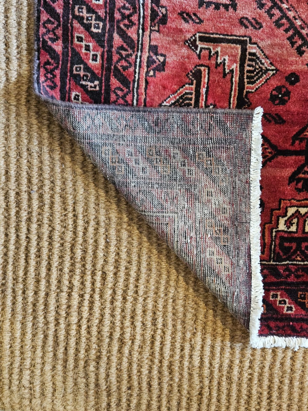 A hand-knotted deep red and dark brown Baluch tribal wool rug featuring geometric diamond medallions and short white fringe edges. View V