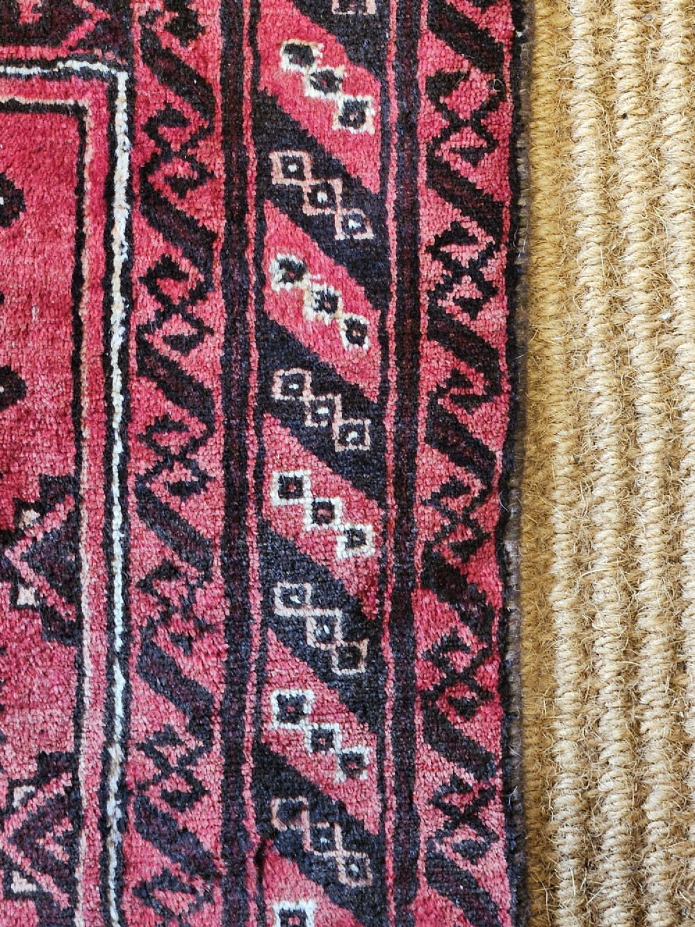 A hand-knotted deep red and dark brown Baluch tribal wool rug featuring geometric diamond medallions and short white fringe edges. View VI