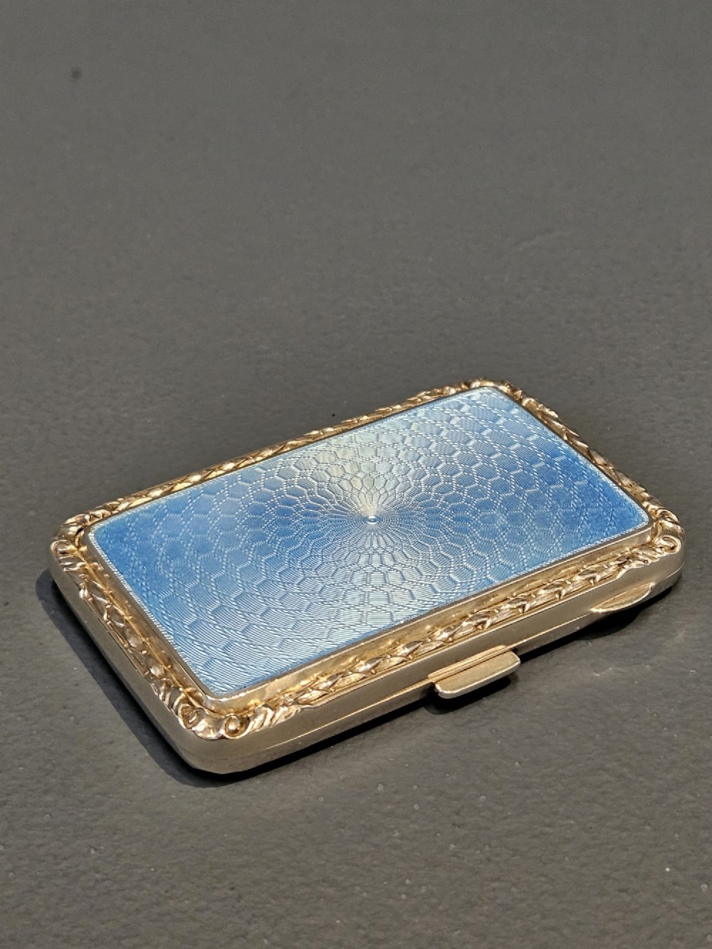 A rectangular silver case featuring a sky-blue engine-turned guilloche enamel panel and an ornate chased border. View IV