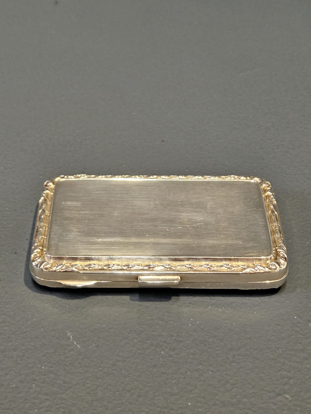 A rectangular silver case featuring a sky-blue engine-turned guilloche enamel panel and an ornate chased border. View VI
