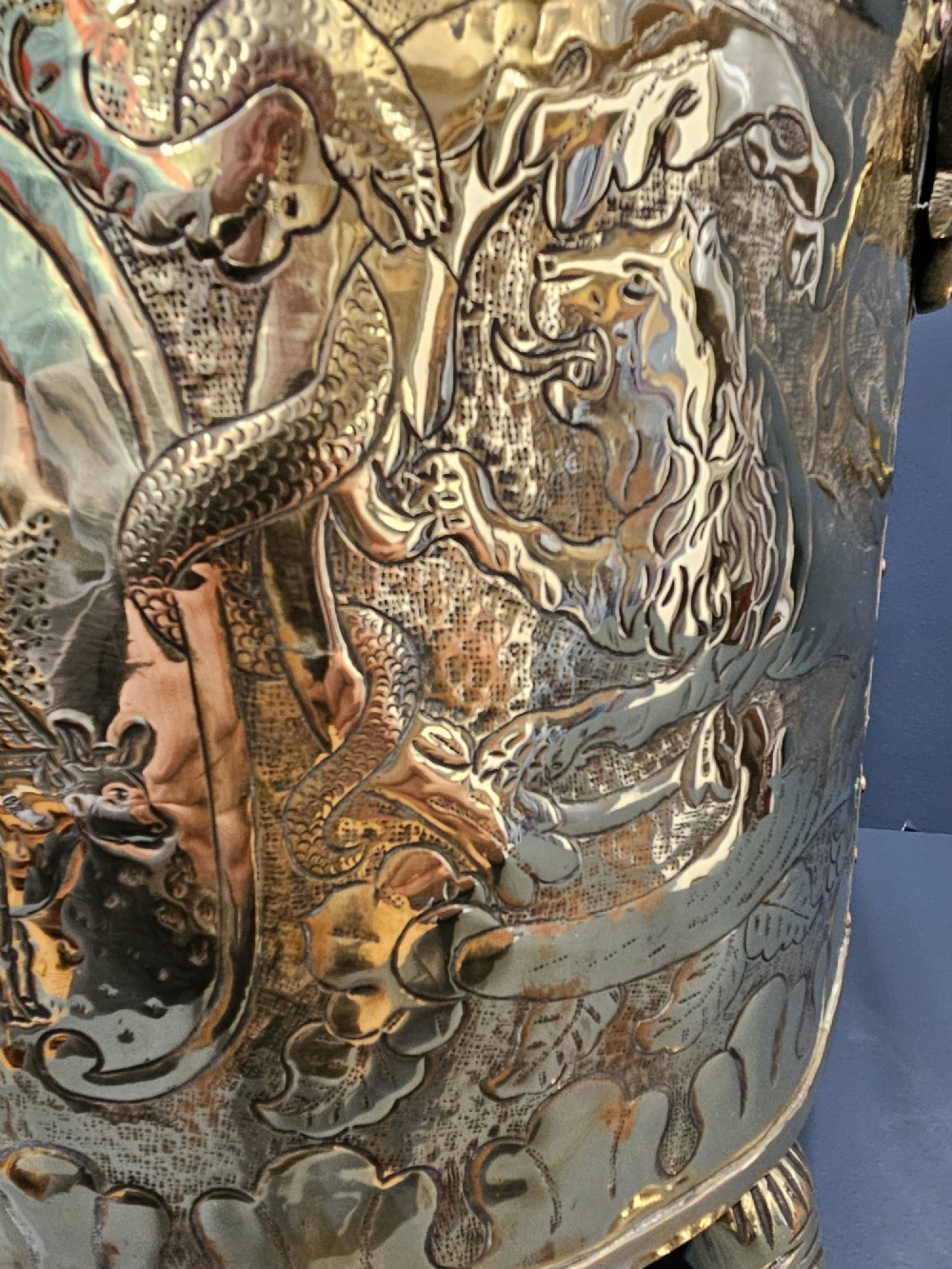 A circular Victorian brass log bin featuring embossed pictorial scenes, a copper rim, cast lion mask side handles, and paw feet. View III