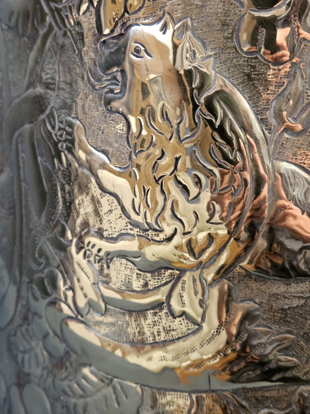 A circular Victorian brass log bin featuring embossed pictorial scenes, a copper rim, cast lion mask side handles, and paw feet. View VII