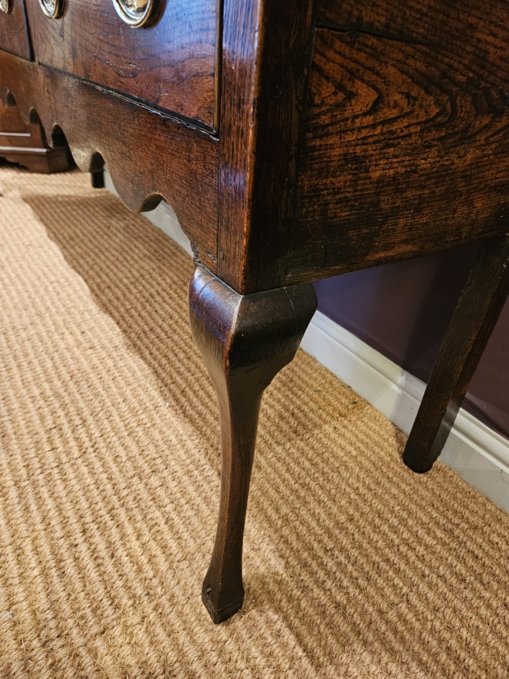 An 18th-century George II elm low dresser featuring three drawers with brass bail handles and shaped cabriole legs. View IV