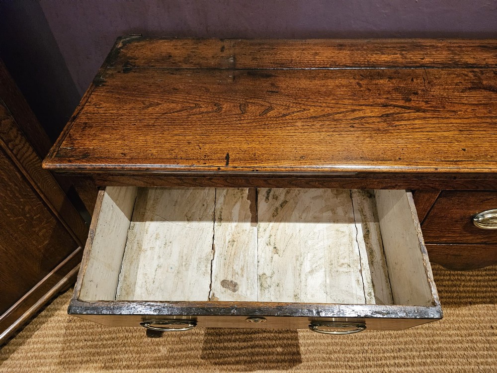 An 18th-century George II elm low dresser featuring three drawers with brass bail handles and shaped cabriole legs. View VIII