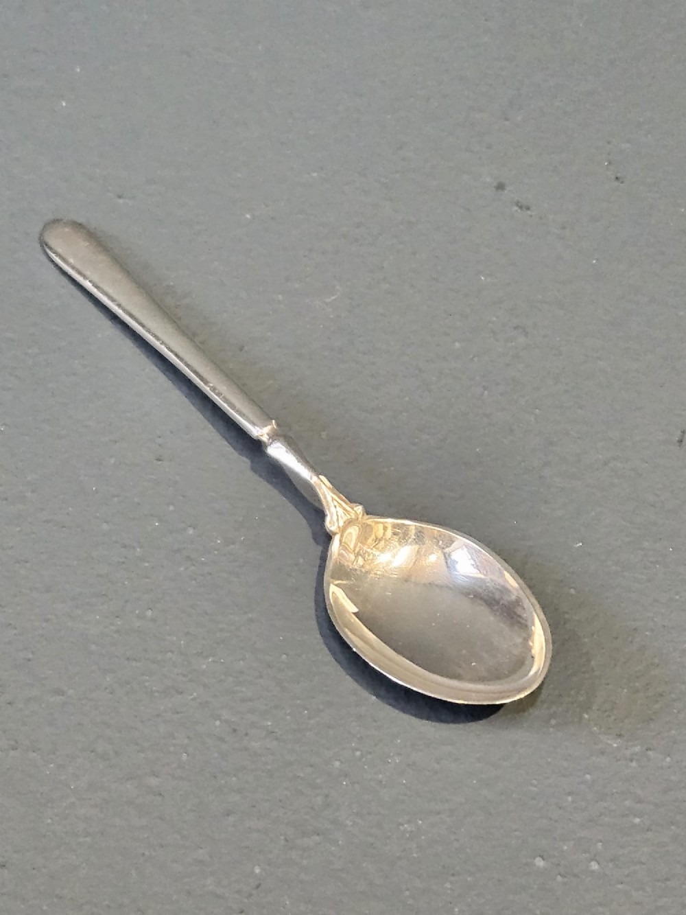 A set of six silver coffee spoons displayed inside a dark fitted presentation case lined with blue velvet and white silk. View III