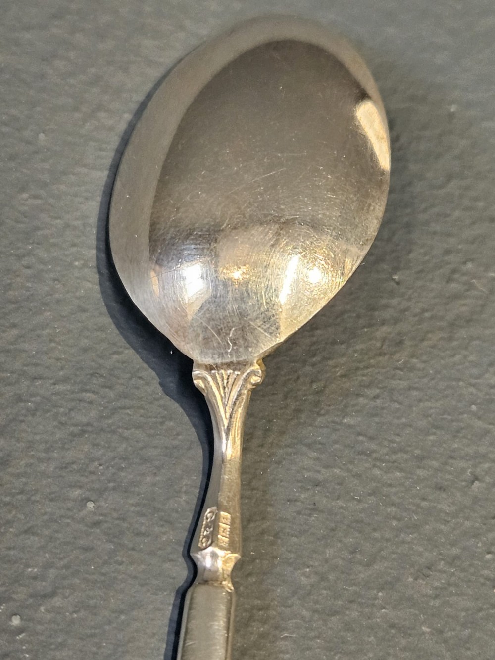 A set of six silver coffee spoons displayed inside a dark fitted presentation case lined with blue velvet and white silk. View V