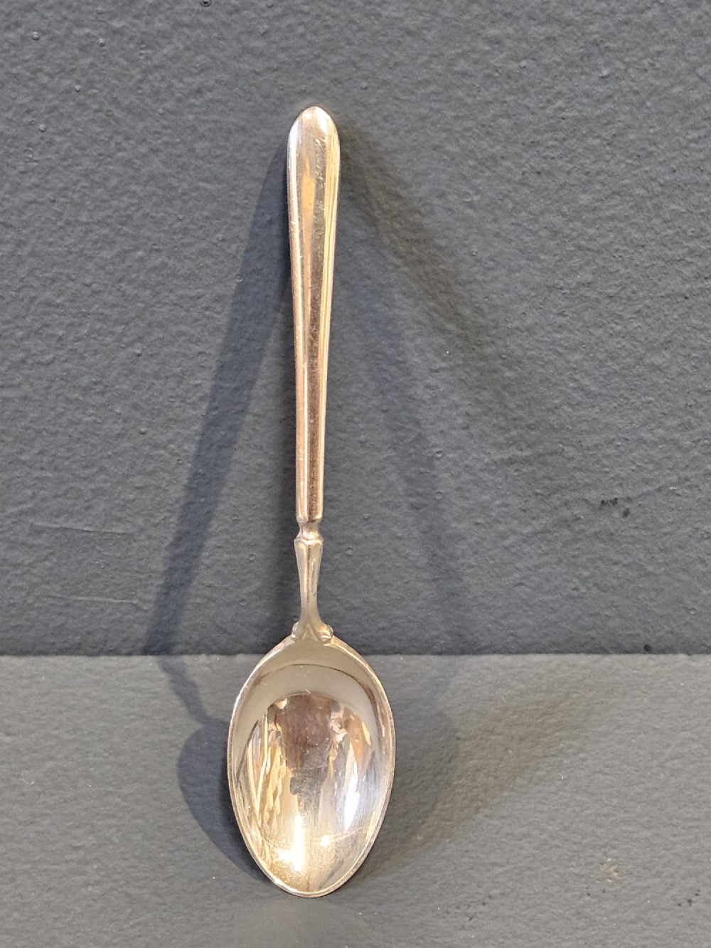 A set of six silver coffee spoons displayed inside a dark fitted presentation case lined with blue velvet and white silk. View VII
