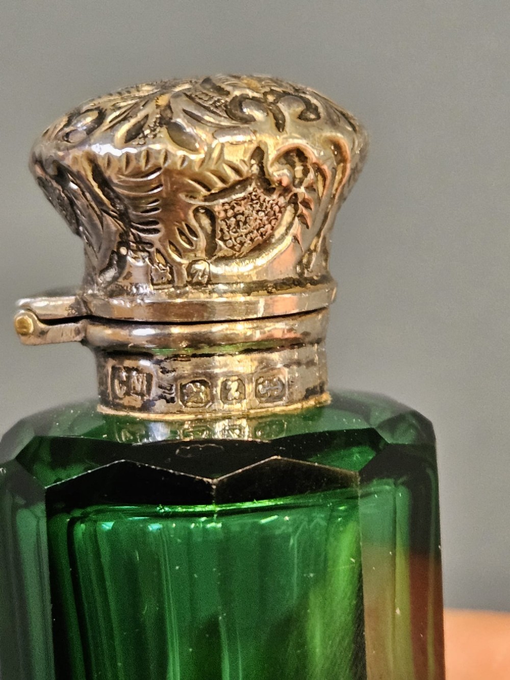A Victorian double-ended emerald green facet-cut glass scent bottle with detailed embossed silver caps on both ends. View VI