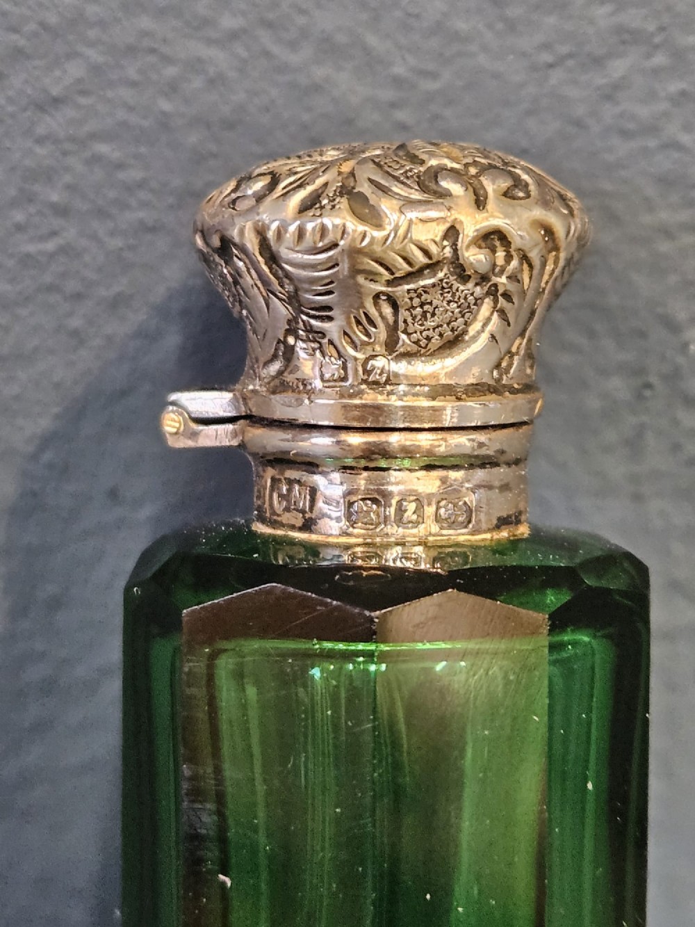 A Victorian double-ended emerald green facet-cut glass scent bottle with detailed embossed silver caps on both ends. View VII