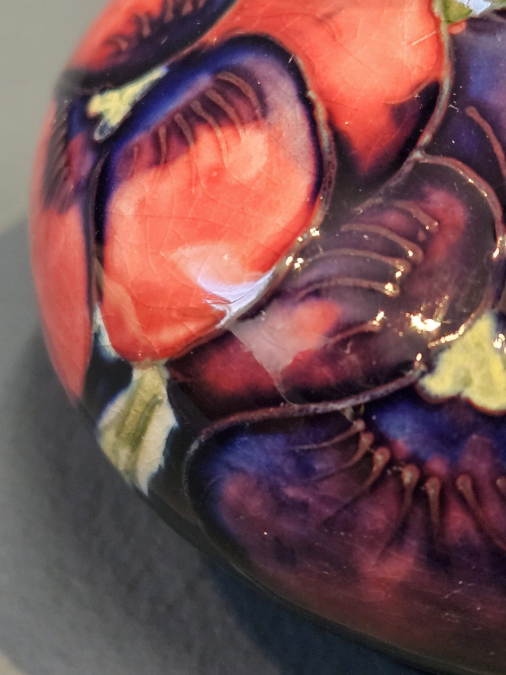 A small squat earthenware vase featuring a dark cobalt blue glaze decorated with hand-painted purple and pink pansy motifs. View V