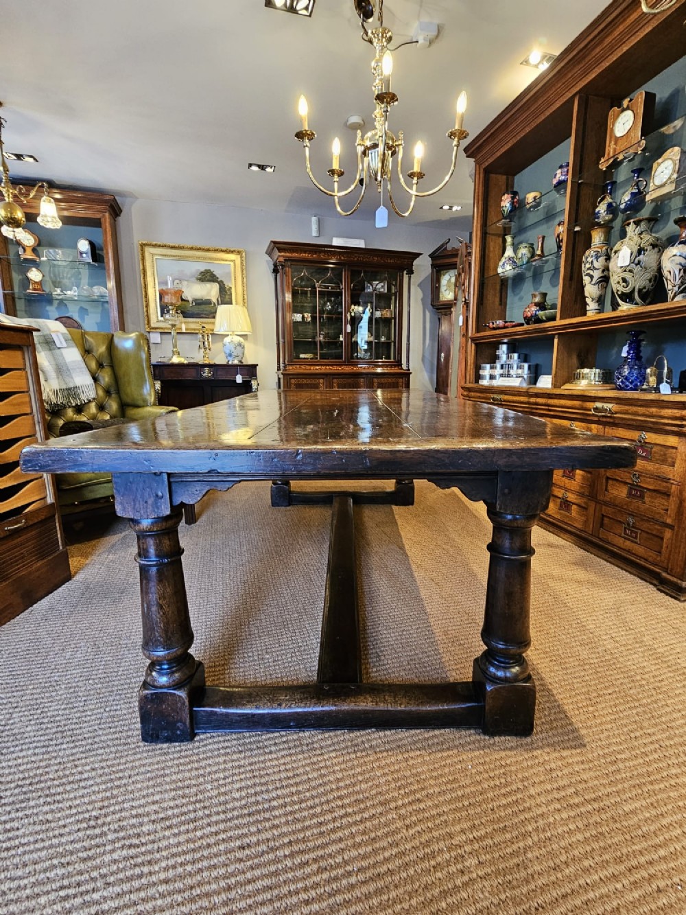 A large George III dark oak refectory dining table featuring a solid plank top, turned legs, and a low H-stretcher base. View IV