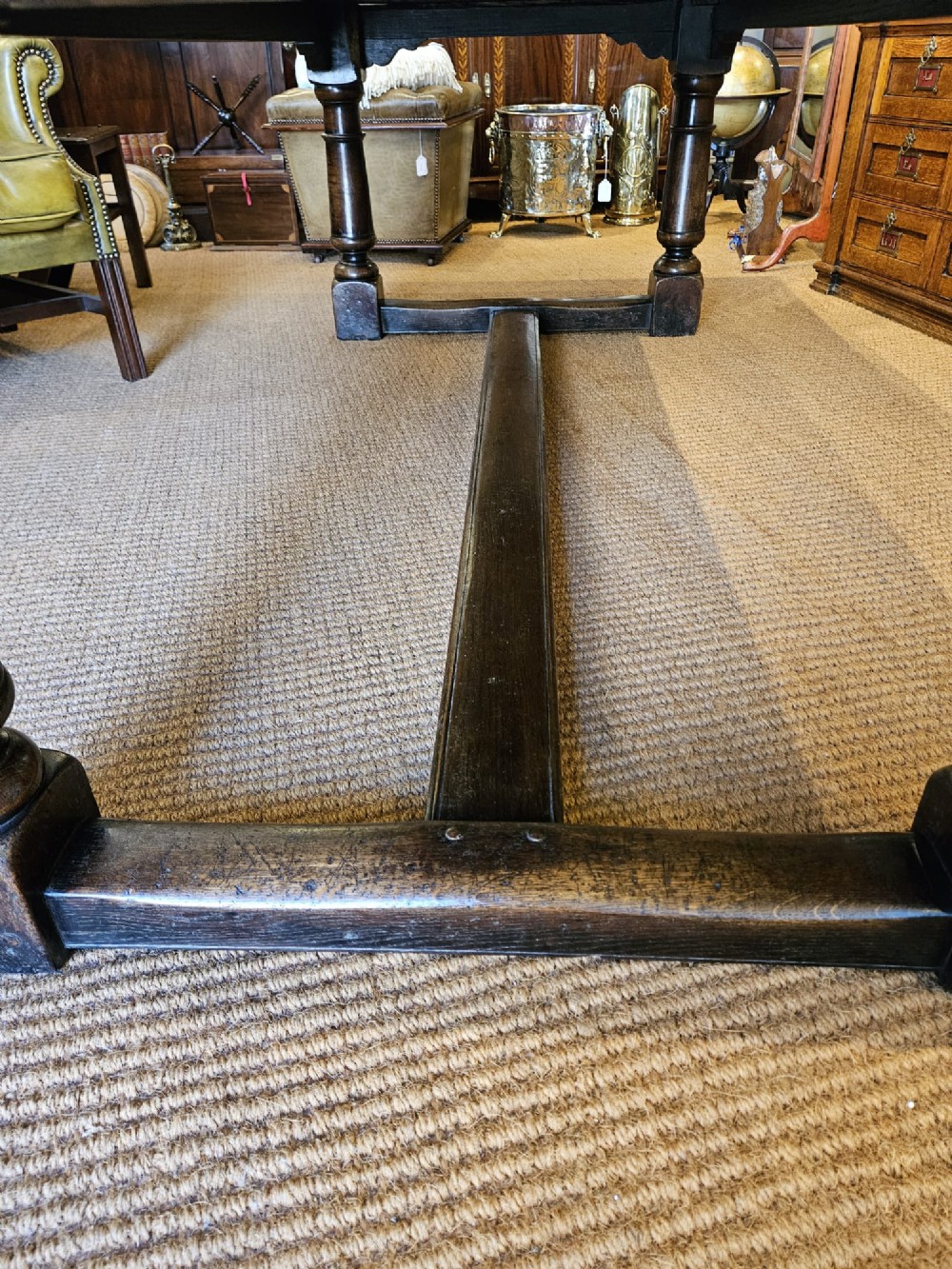 A large George III dark oak refectory dining table featuring a solid plank top, turned legs, and a low H-stretcher base. View VI