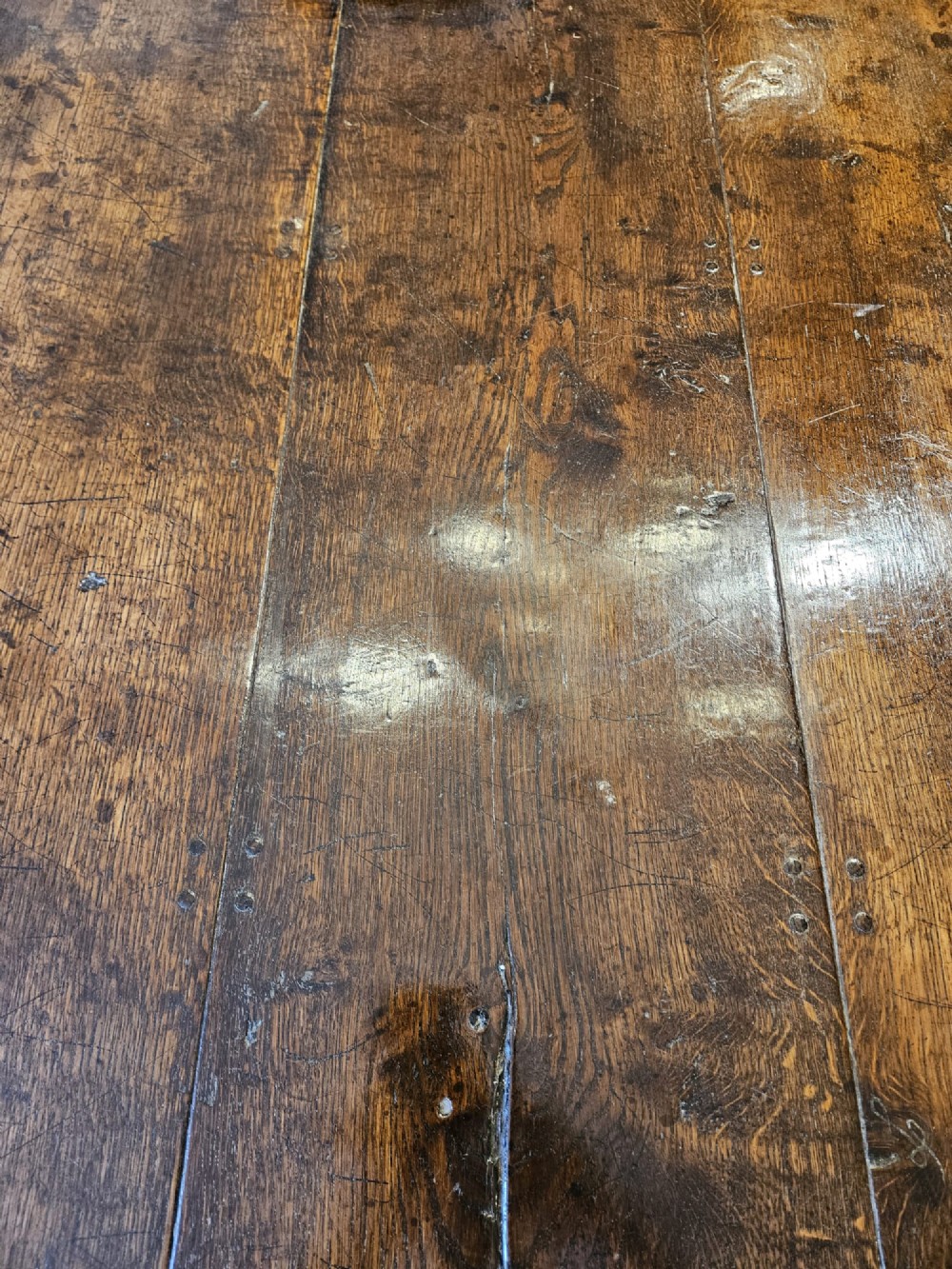 A large George III dark oak refectory dining table featuring a solid plank top, turned legs, and a low H-stretcher base. View VIII