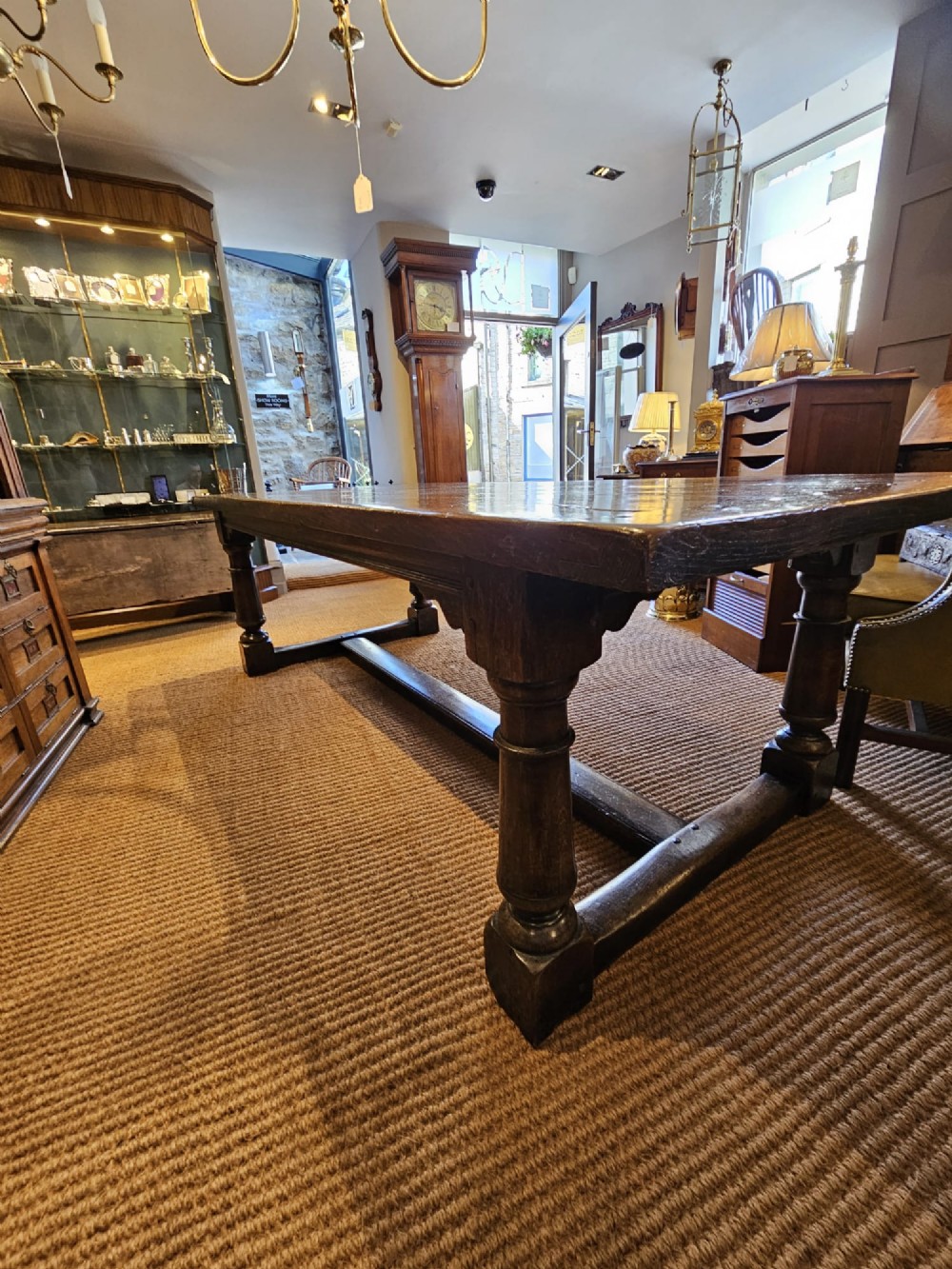 A large George III dark oak refectory dining table featuring a solid plank top, turned legs, and a low H-stretcher base. View X