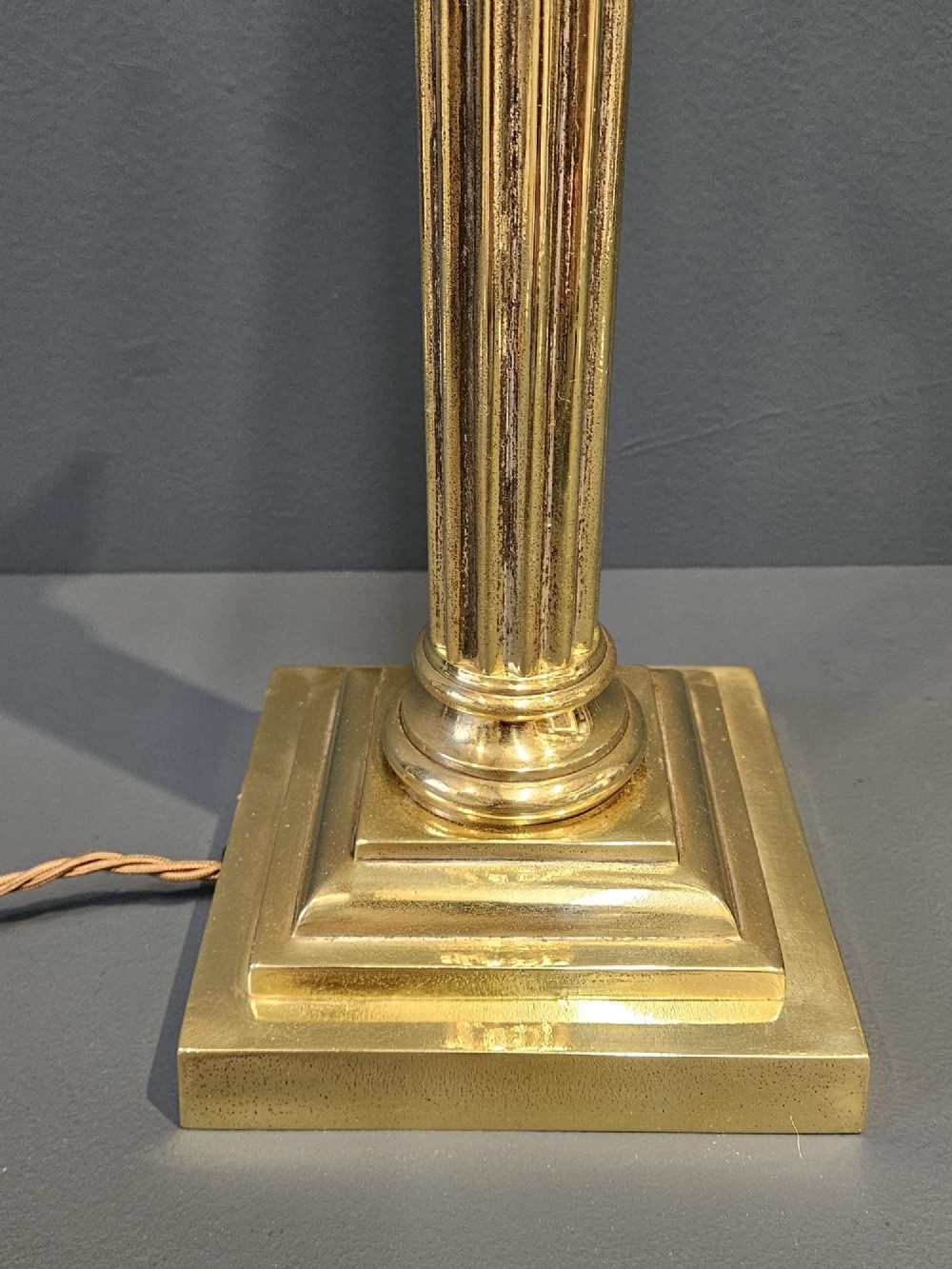 A brass table lamp base designed as a fluted Corinthian column on a square stepped pedestal base. View II