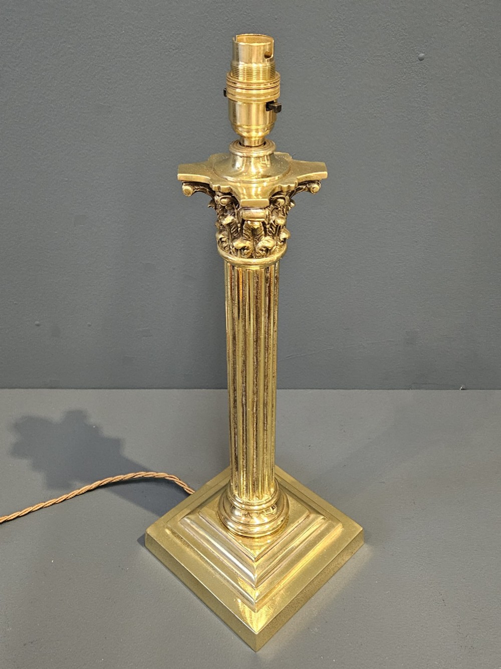 A brass table lamp base designed as a fluted Corinthian column on a square stepped pedestal base. View V