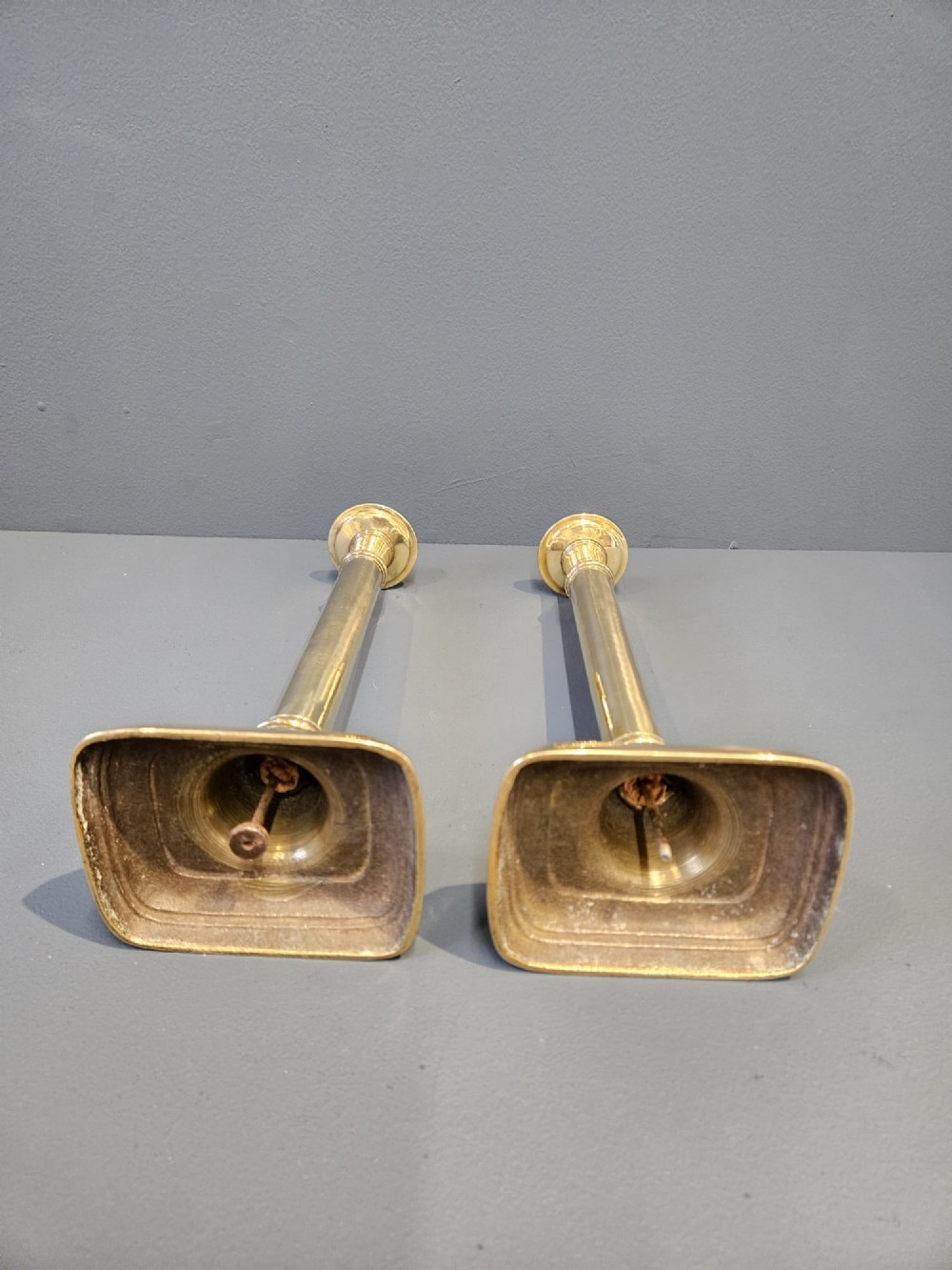 A pair of tall George III brass candlesticks with stepped square bases and slender cylindrical columns featuring raised band details. View III