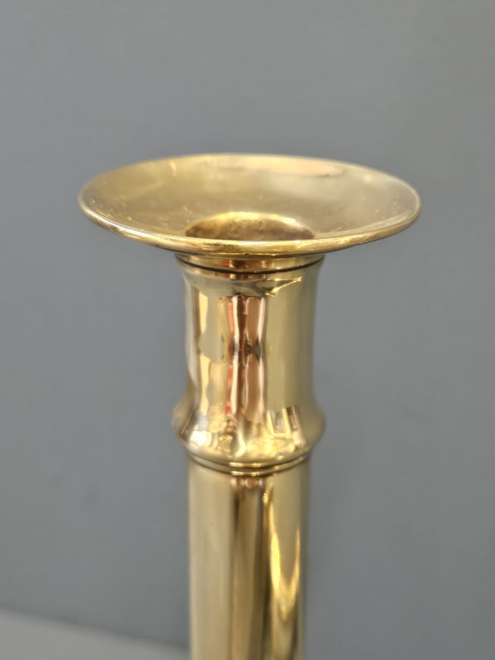 A pair of tall George III brass candlesticks with stepped square bases and slender cylindrical columns featuring raised band details. View VI