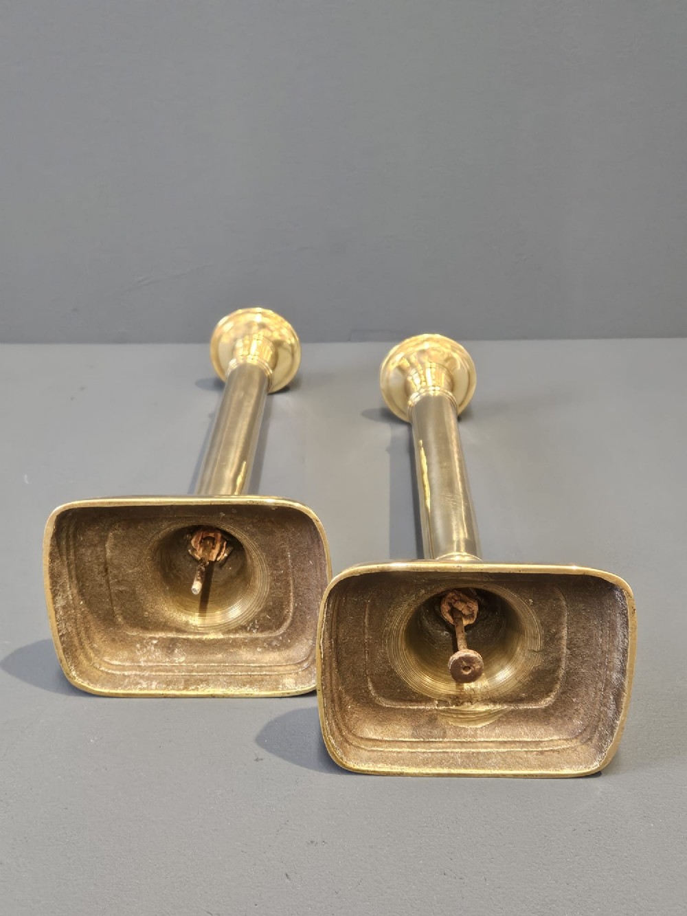 A pair of tall George III brass candlesticks with stepped square bases and slender cylindrical columns featuring raised band details. View VII