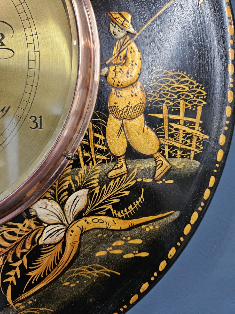 A circular Edwardian aneroid barometer set in a black lacquered frame with gilded hand-painted Chinoiserie figures and landscape motifs. View VI