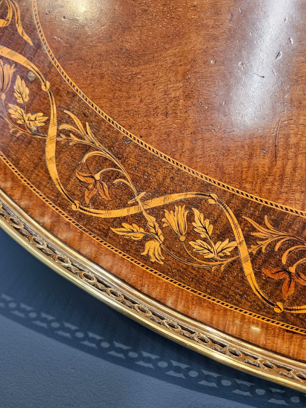An oval Victorian mahogany serving tray featuring detailed floral marquetry inlay, a central shell motif, and a pierced brass gallery rim with two handles. View III