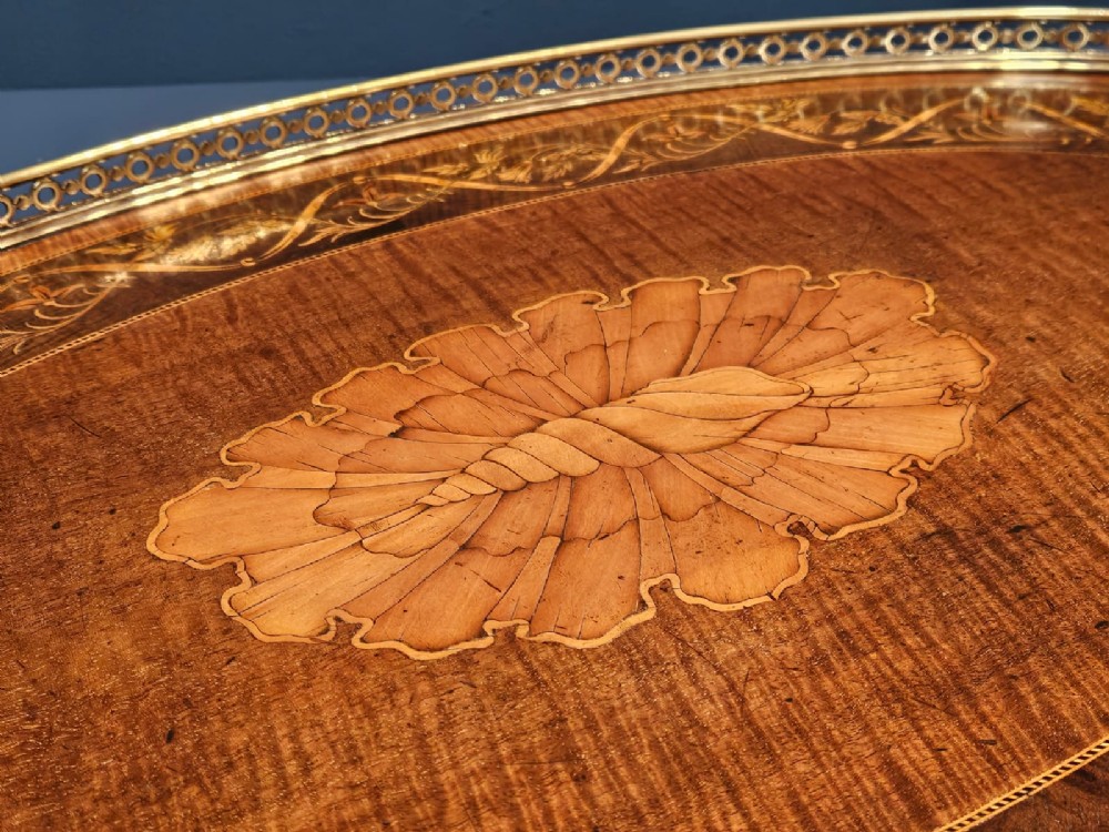 An oval Victorian mahogany serving tray featuring detailed floral marquetry inlay, a central shell motif, and a pierced brass gallery rim with two handles. View V