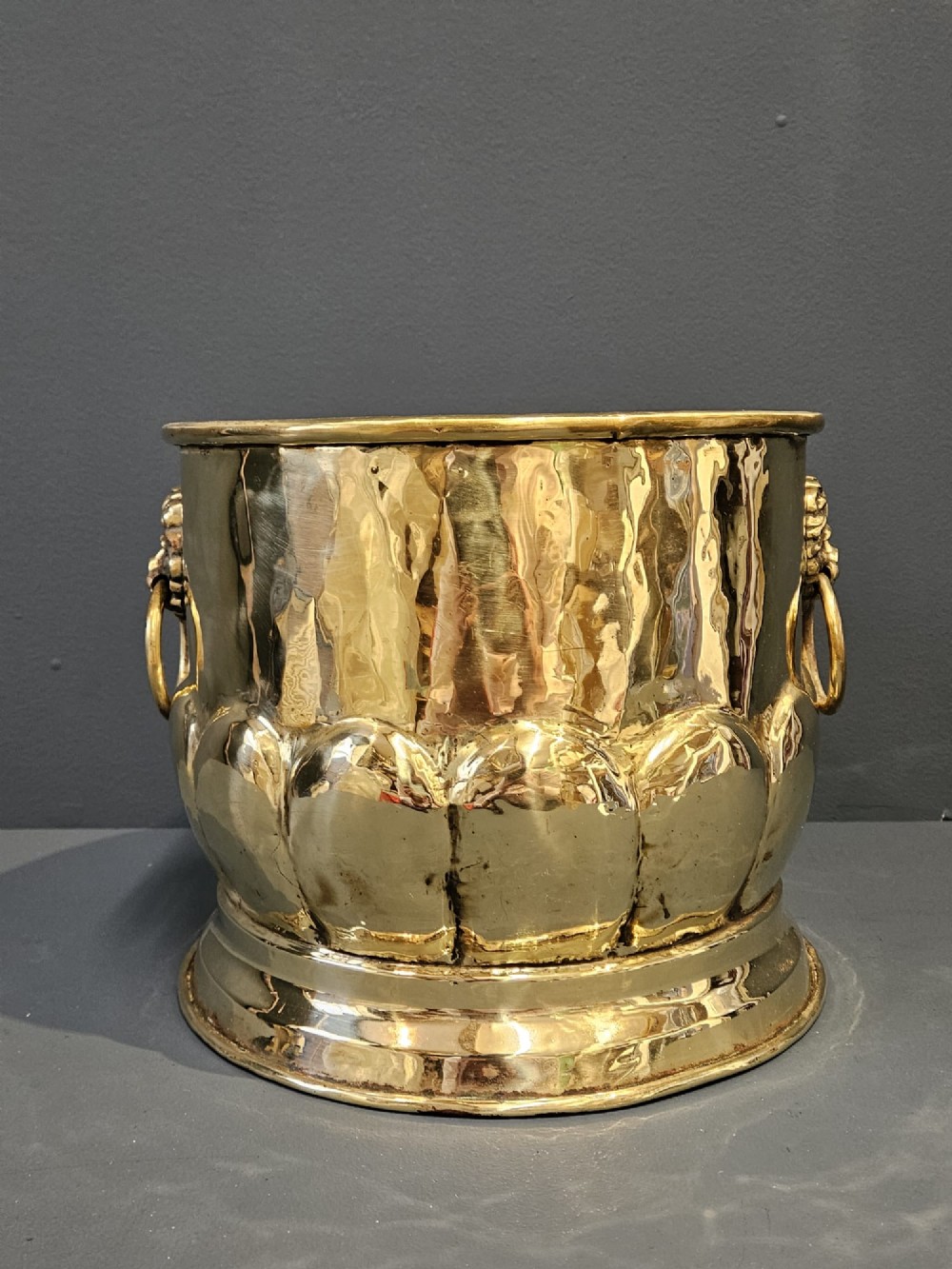 A Victorian brass planter featuring a polished finish, lobed lower body, and cast lion mask ring handles. View III