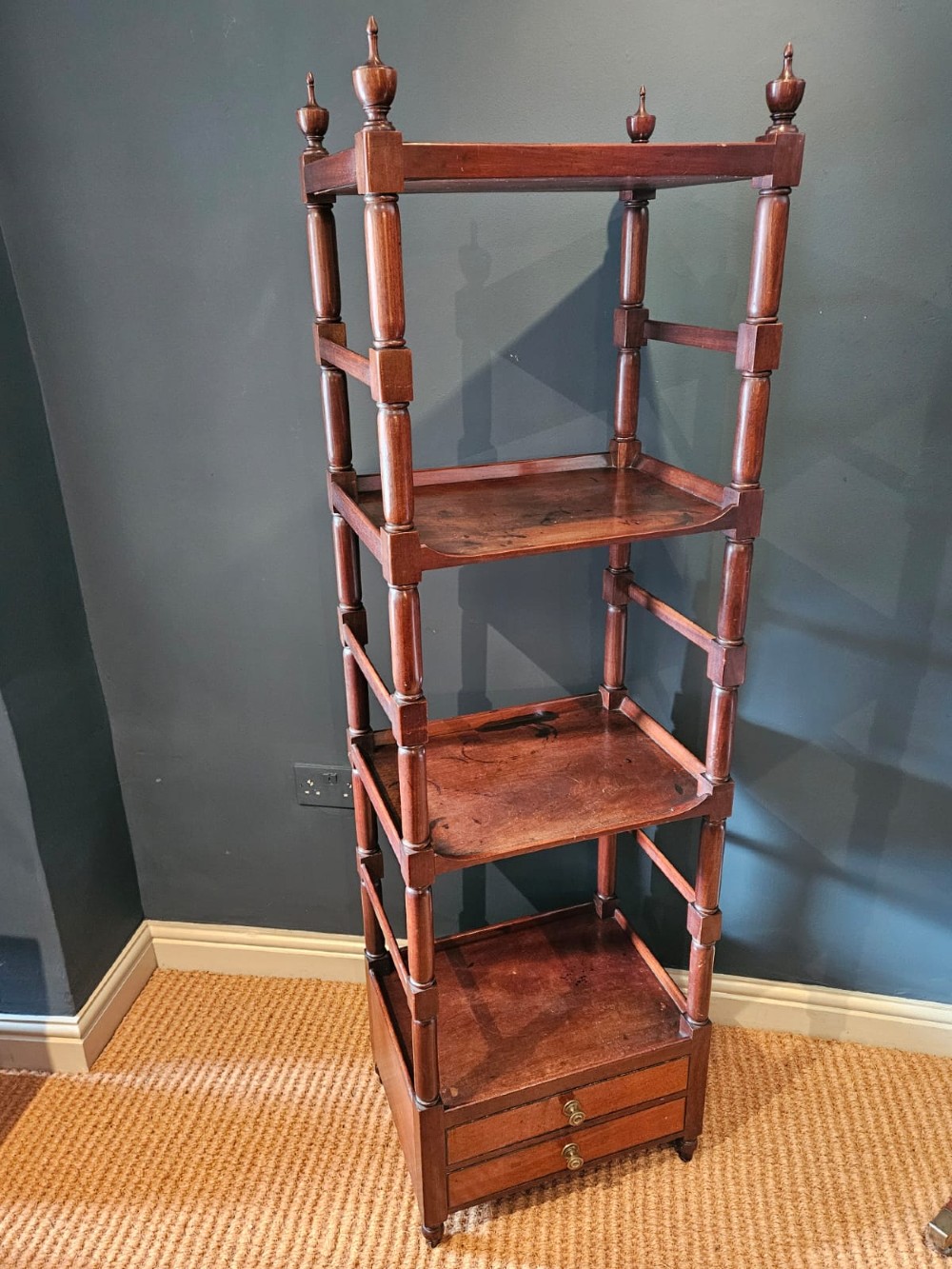 A tall Regency four-tier mahogany whatnot stand with slender turned posts, finial top ornaments, open shelves, and a base drawer.