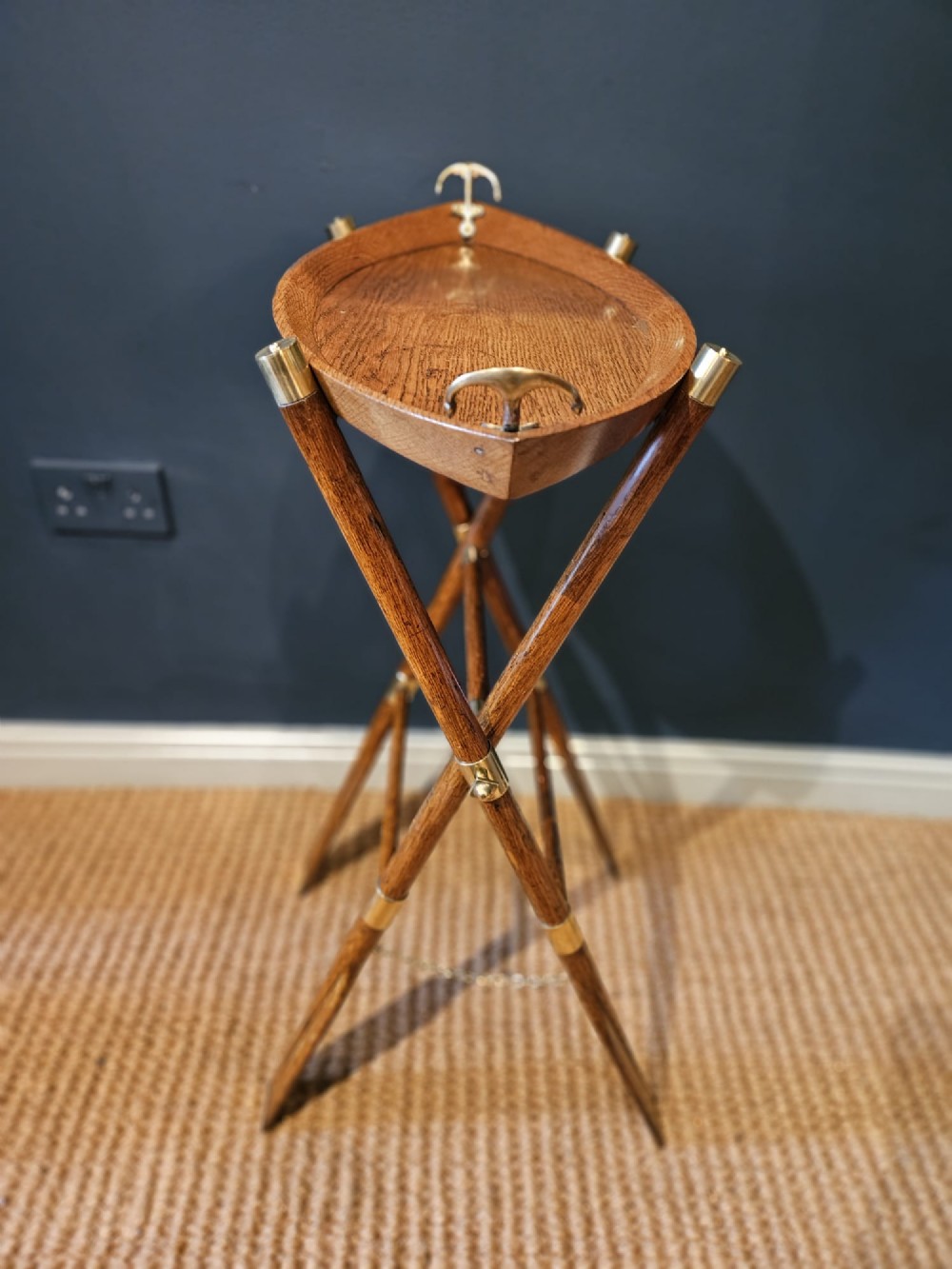 A boat-shaped oak tray with brass handles resting on a folding wooden stand constructed from crossed oars. View III