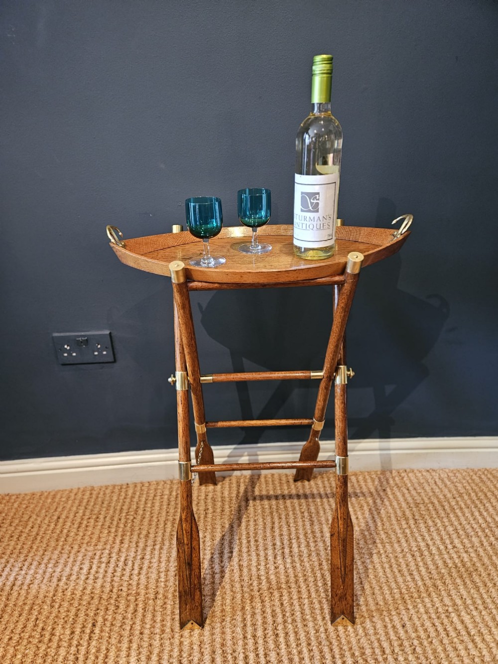 A boat-shaped oak tray with brass handles resting on a folding wooden stand constructed from crossed oars. View X