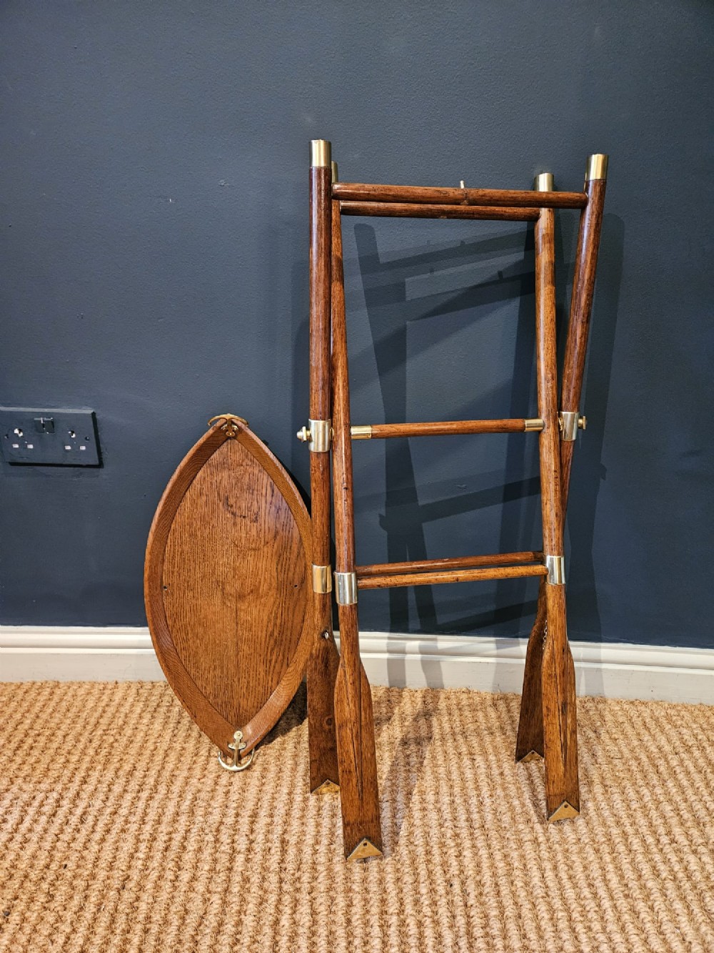 A boat-shaped oak tray with brass handles resting on a folding wooden stand constructed from crossed oars. View XI