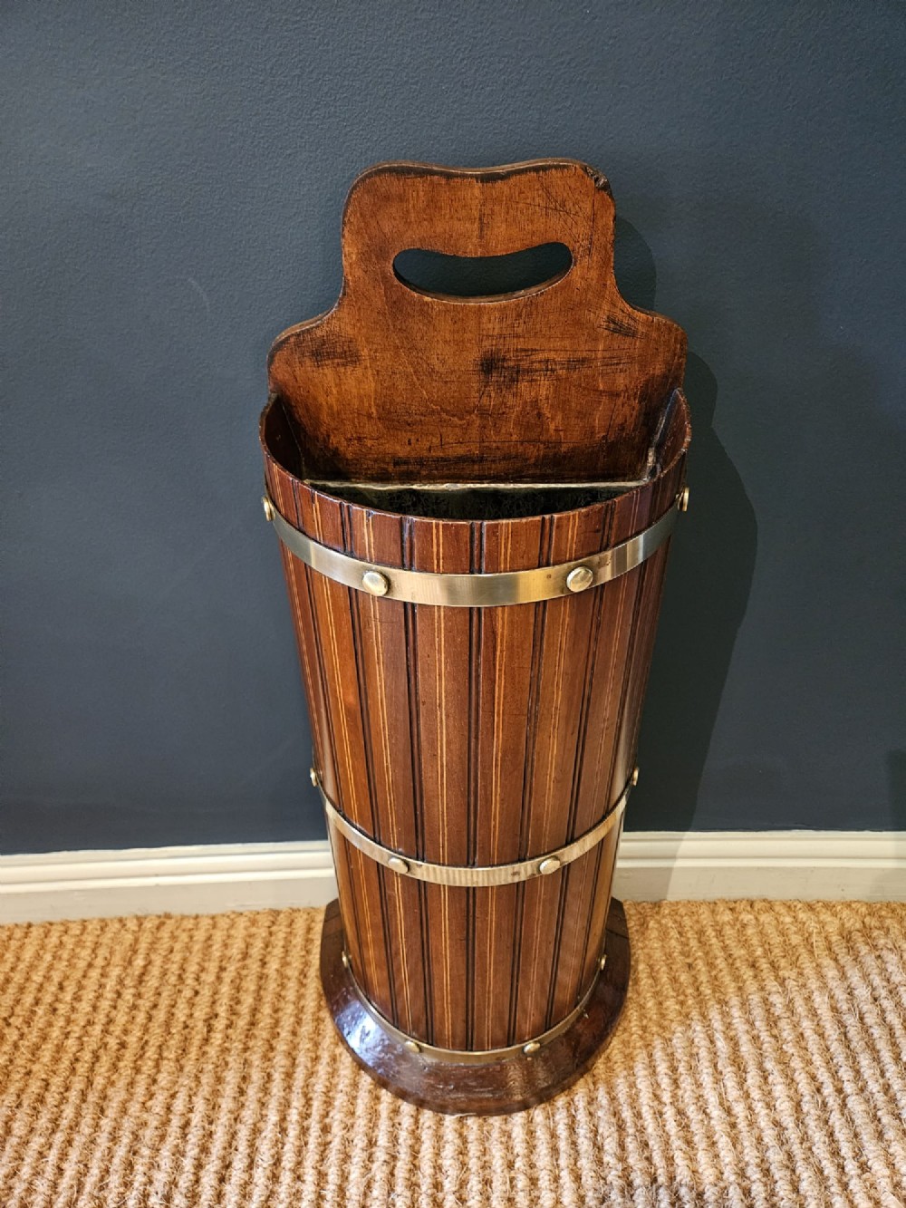 A cylindrical reeded mahogany stick stand featuring brass binding bands and a carved cut-out carrying handle. View IV
