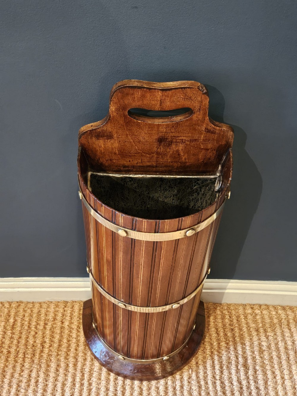 A cylindrical reeded mahogany stick stand featuring brass binding bands and a carved cut-out carrying handle. View VI