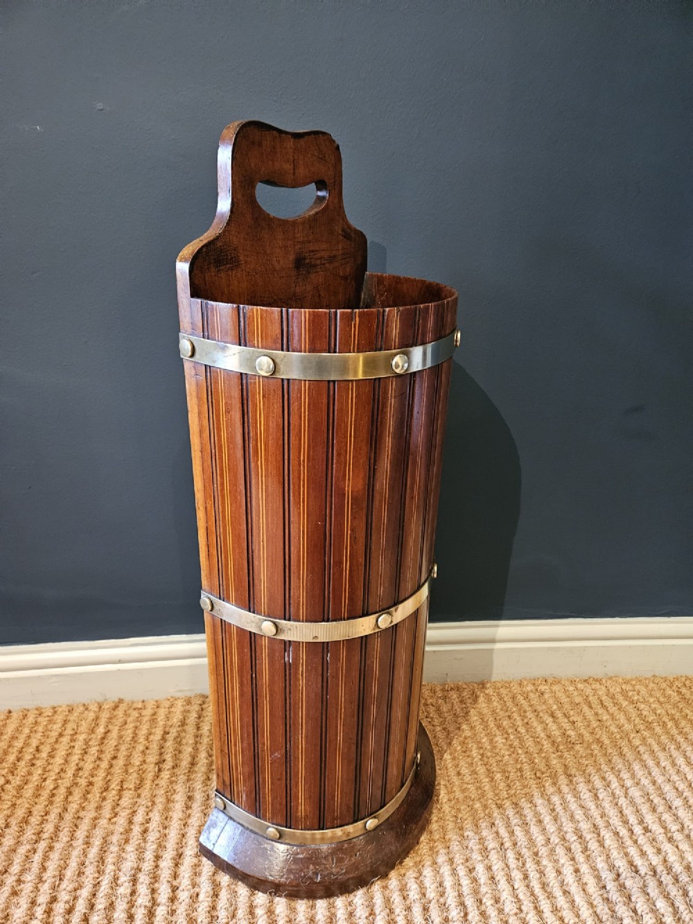 A cylindrical reeded mahogany stick stand featuring brass binding bands and a carved cut-out carrying handle. View VII