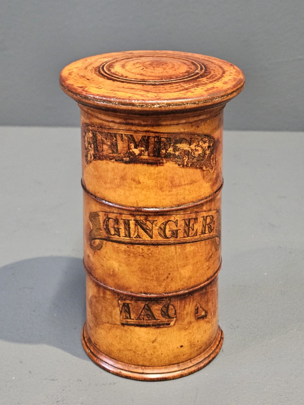 A cylindrical turned fruitwood spice tower featuring stacked compartments labelled Nutmeg, Ginger, and Mace. View II