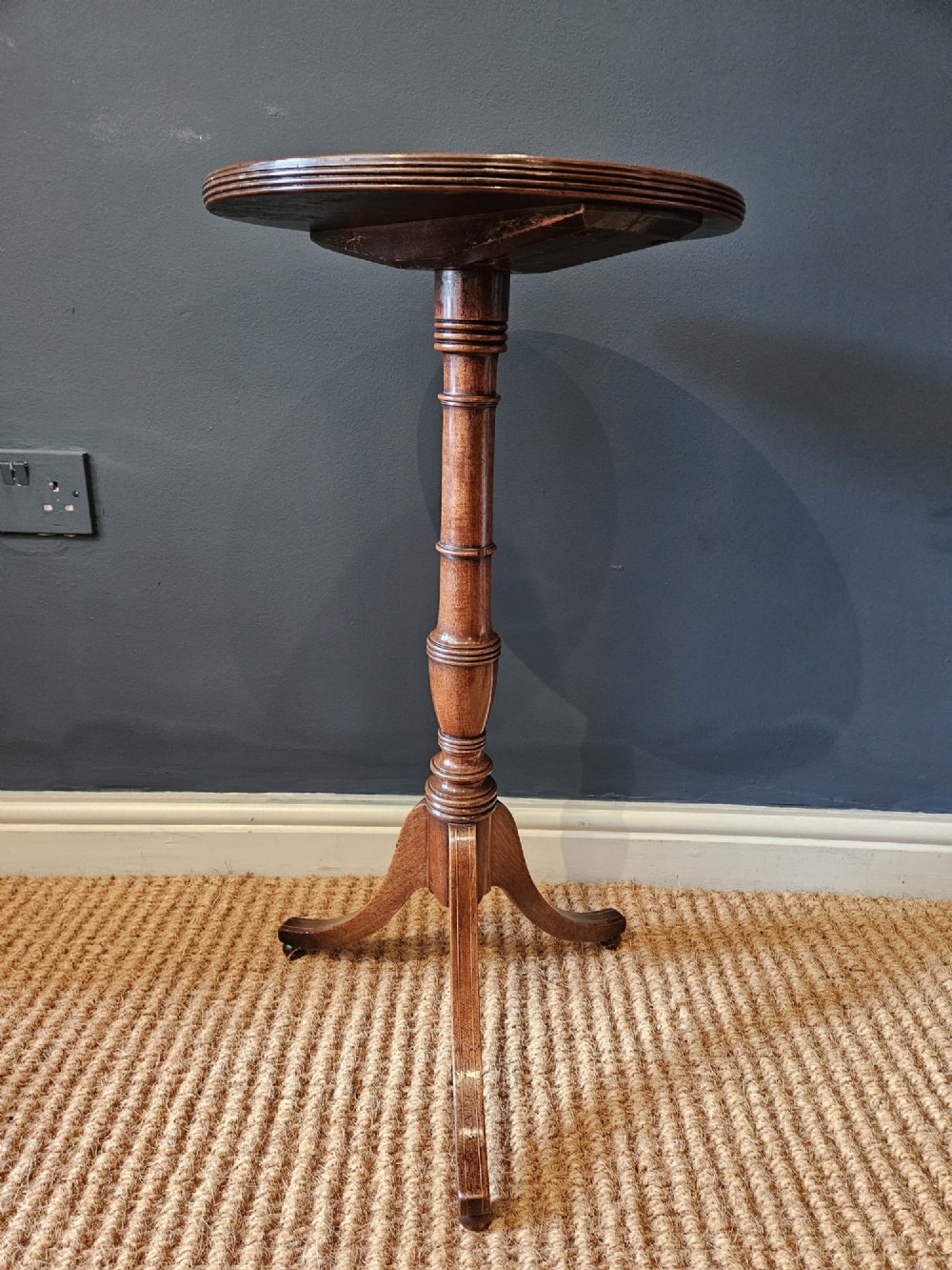 A George III mahogany wine table featuring a dished circular top, a turned central column, and a tripod base with three splayed legs. View IV