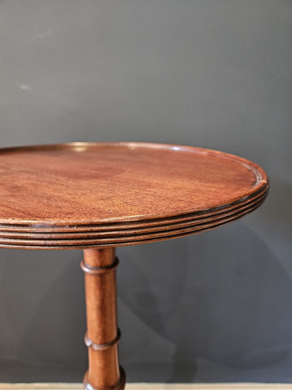 A George III mahogany wine table featuring a dished circular top, a turned central column, and a tripod base with three splayed legs. View V