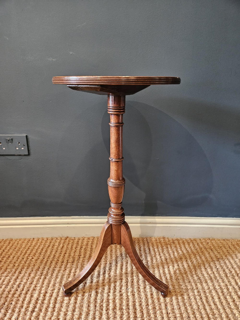 A George III mahogany wine table featuring a dished circular top, a turned central column, and a tripod base with three splayed legs. View VII