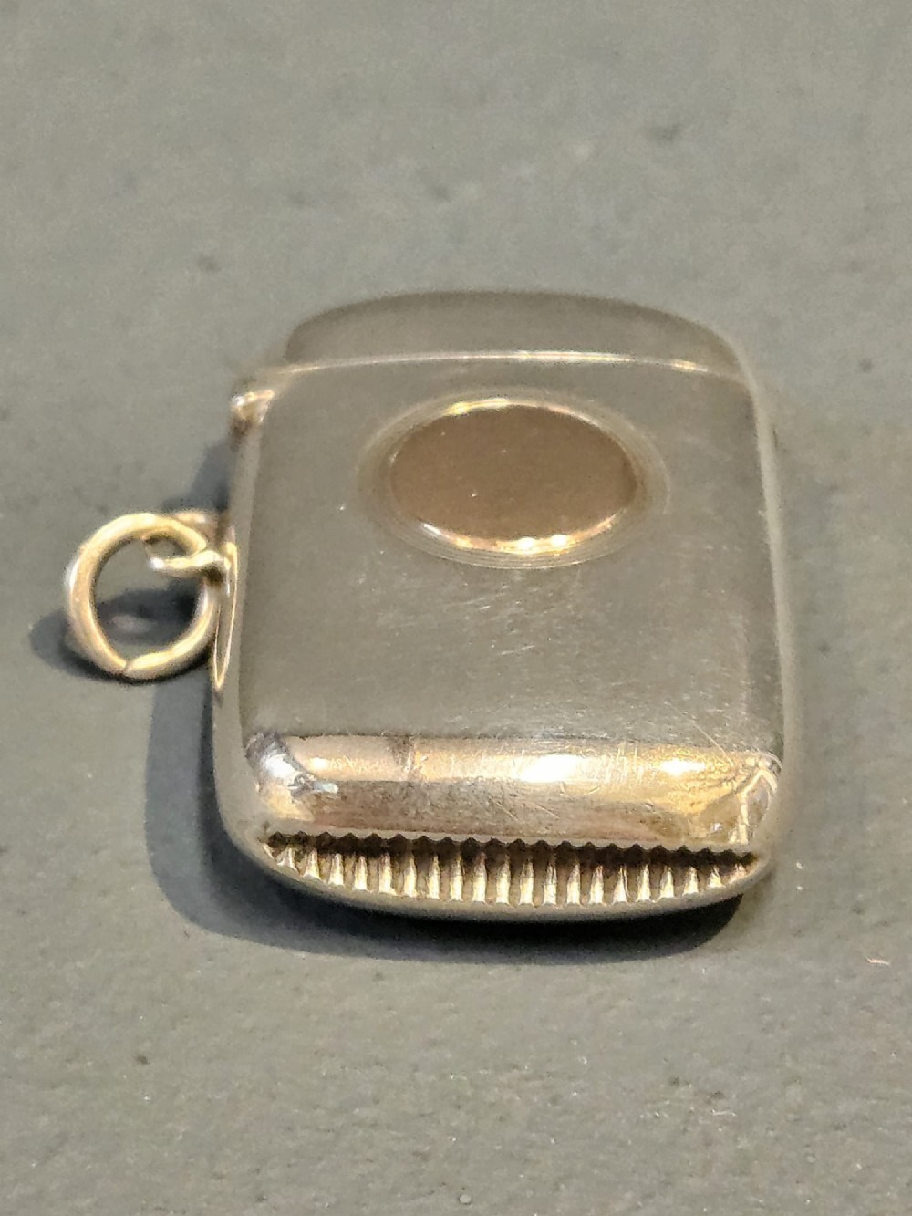 A polished silver vesta case featuring a central circular gold plaque and a side ring attachment. View IV