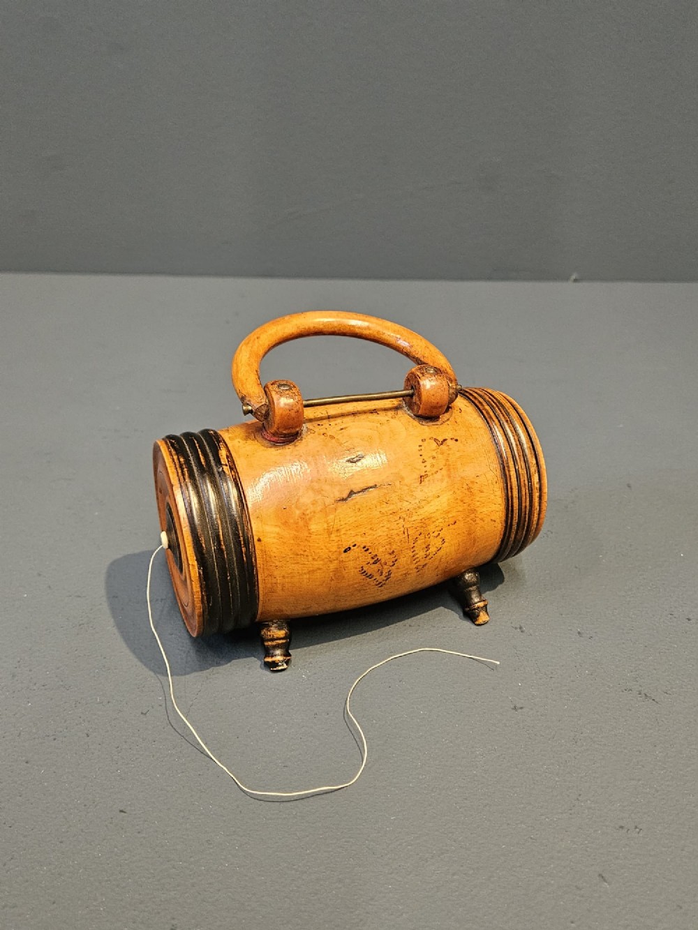 A turned Victorian fruitwood string barrel resting on four short turned feet with an arched top handle and dark ring details.