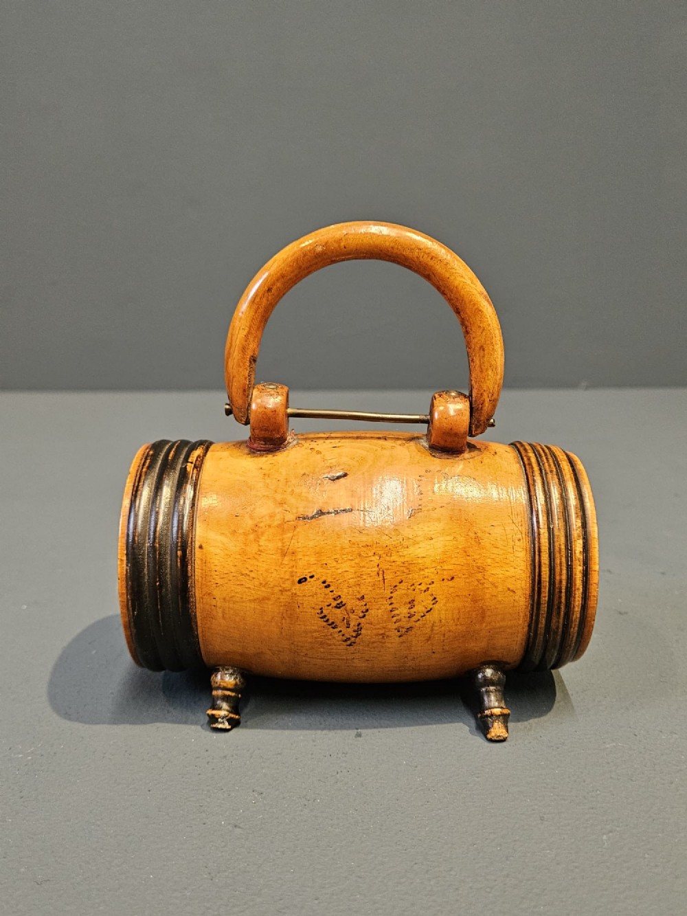 A turned Victorian fruitwood string barrel resting on four short turned feet with an arched top handle and dark ring details. View III