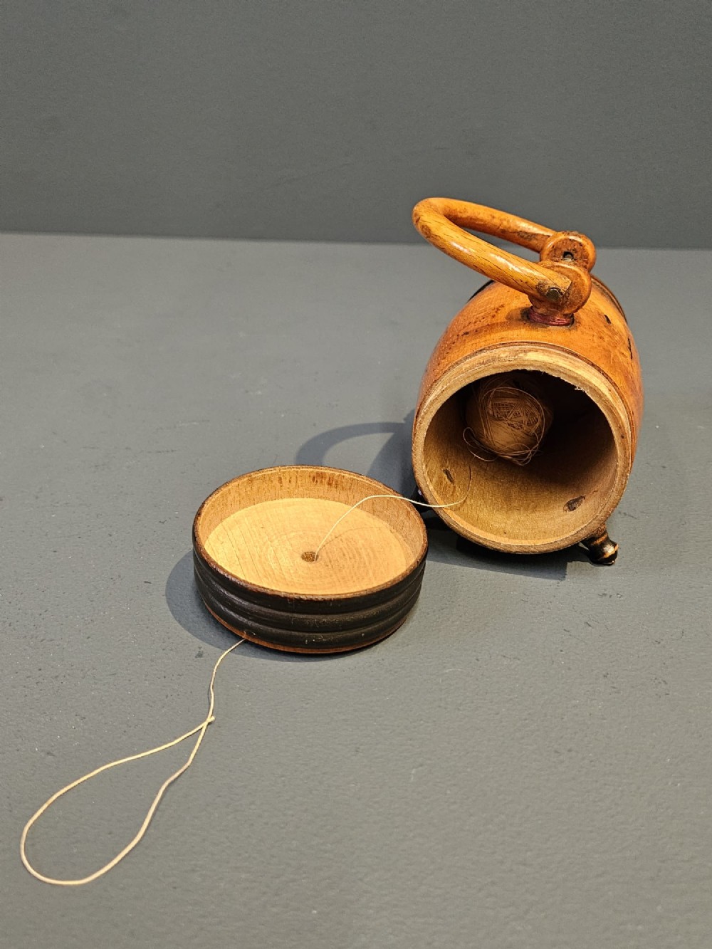 A turned Victorian fruitwood string barrel resting on four short turned feet with an arched top handle and dark ring details. View VI
