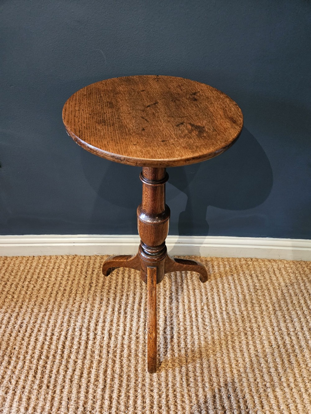 A Regency oak candle table with a circular top, a turned central pedestal stem, and three splayed tripod legs.